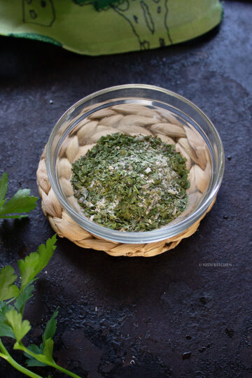 Homemade garlic herb seasoning in a glass jar with dried herbs and garlic.